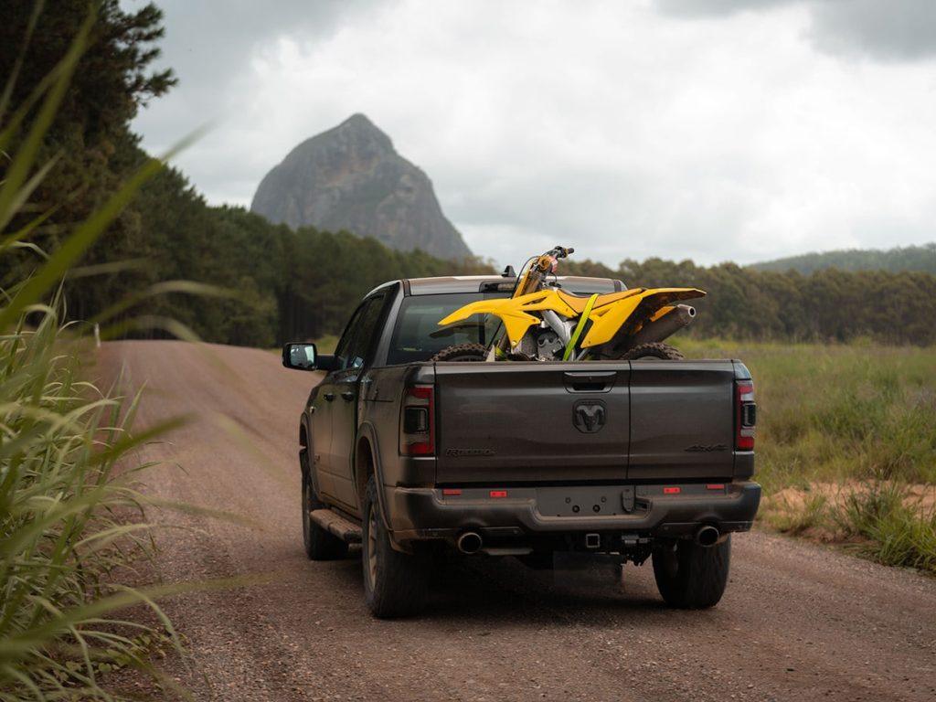 A yellow dirt bike in the cargo bed of a black RAM 1500 Rebel G/T off-roading.