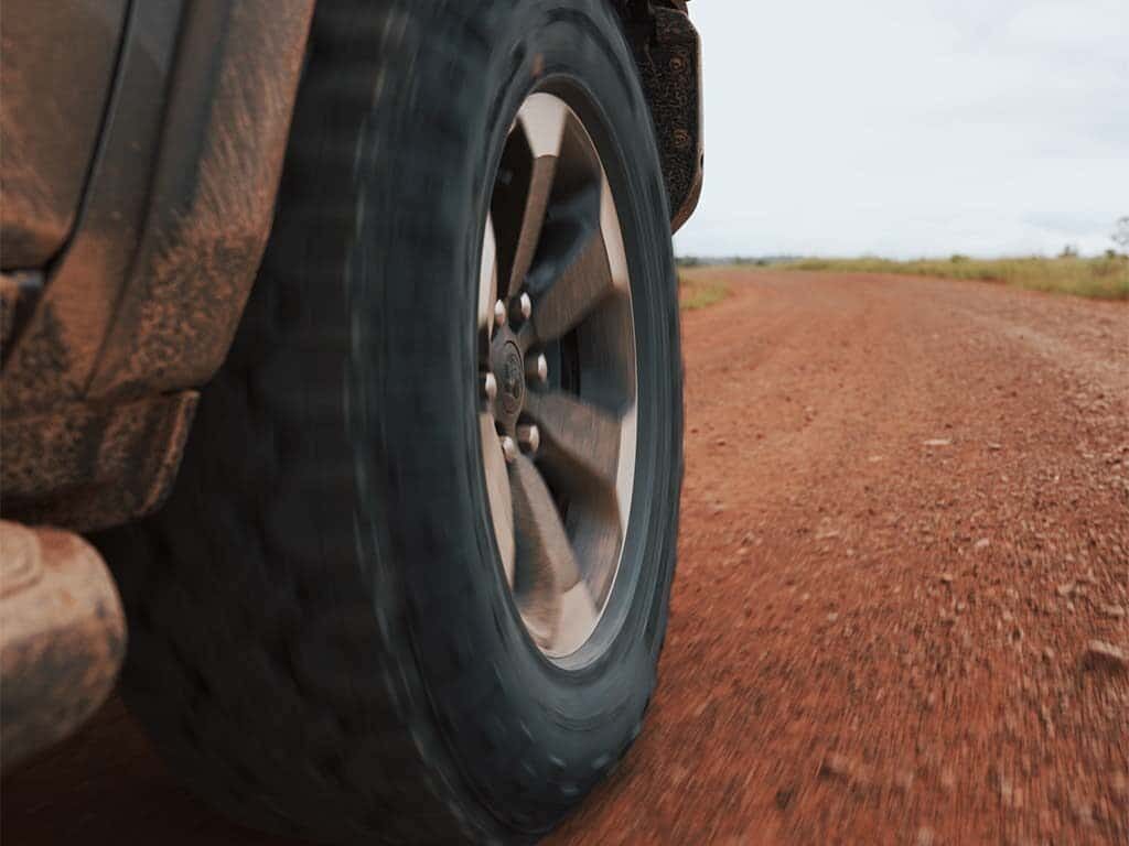 Front-right wheel of a black RAM 1500 Rebel G/T off-roading.